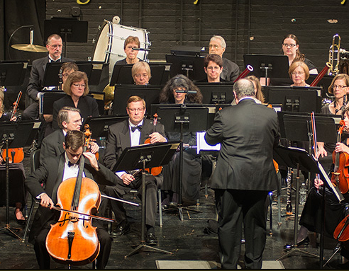 Image of the Royal Oak Symphony Orchestra showing the conductor and seated several musicians.